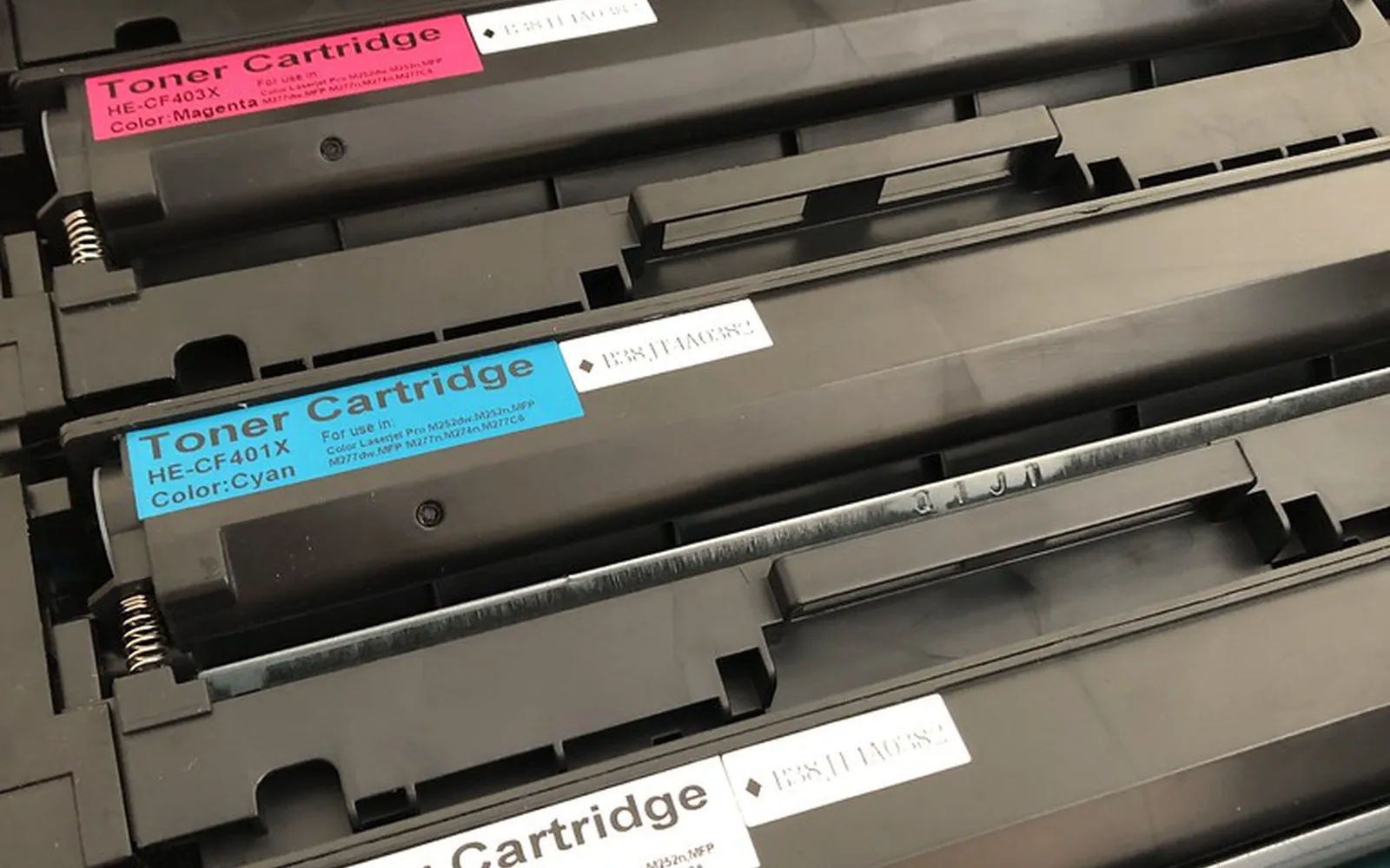 Colour toner cartridges seated side by side in the open drawer of a laser printer