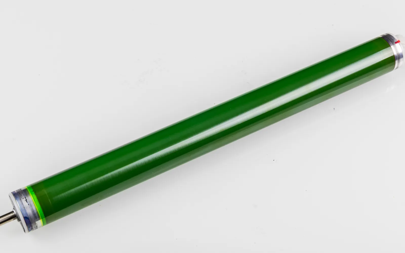 A green photoconductor drum removed from a laser printer, lying on a white surface