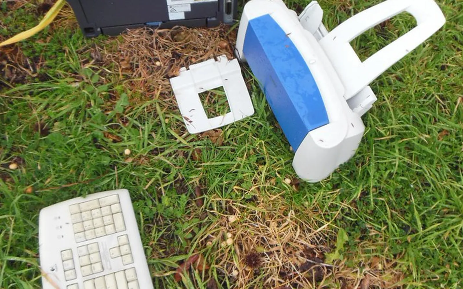 Broken printer parts and an old keyboard dumped on a grass verge