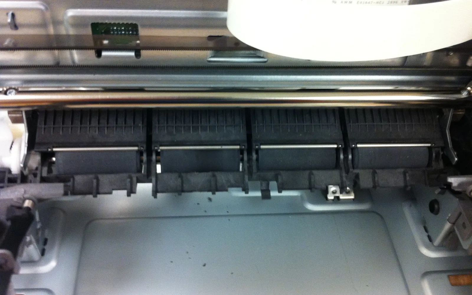 The inside of an inkjet printer showing the carriage rail and ribbon cable that move the print head